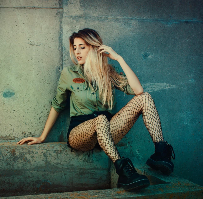 a woman sitting on the steps of a building, an album cover, inspired by Elsa Bleda, trending on pexels, fantastic realism, fish net stockings, wearing military outfit, blonde beautiful young woman, dirty green clothes