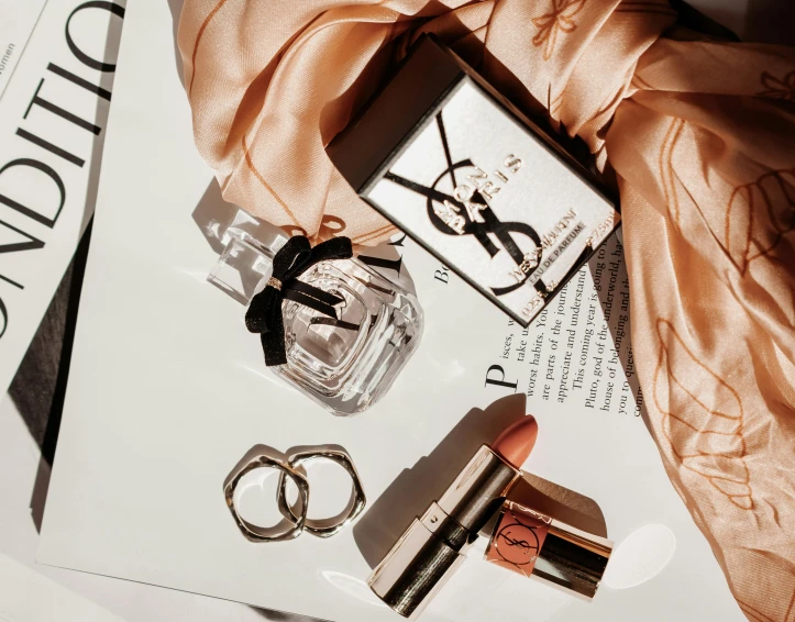 a bottle of perfume sitting on top of a magazine, a still life, by Emma Andijewska, pexels contest winner, wearing two metallic rings, toys, thumbnail, lipstick