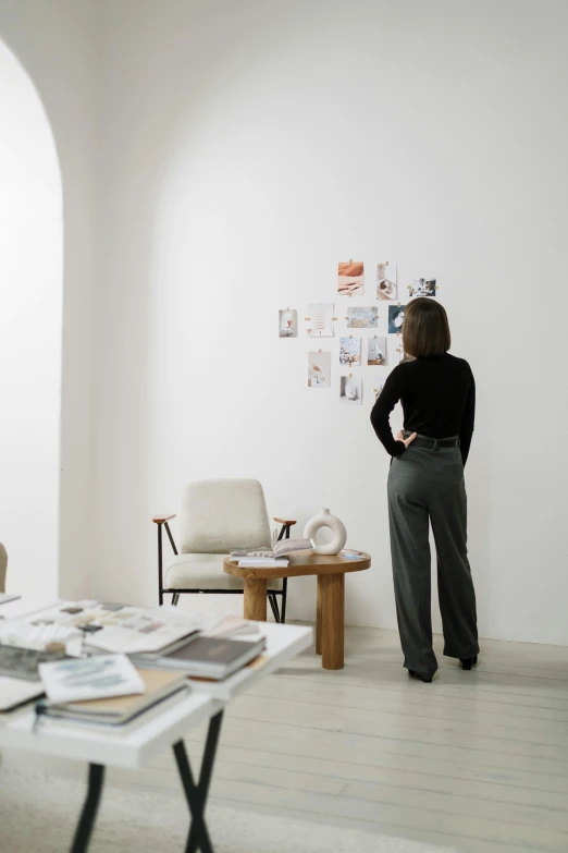 a woman standing in a room next to a table, planning, profile image, moodboard, full body image