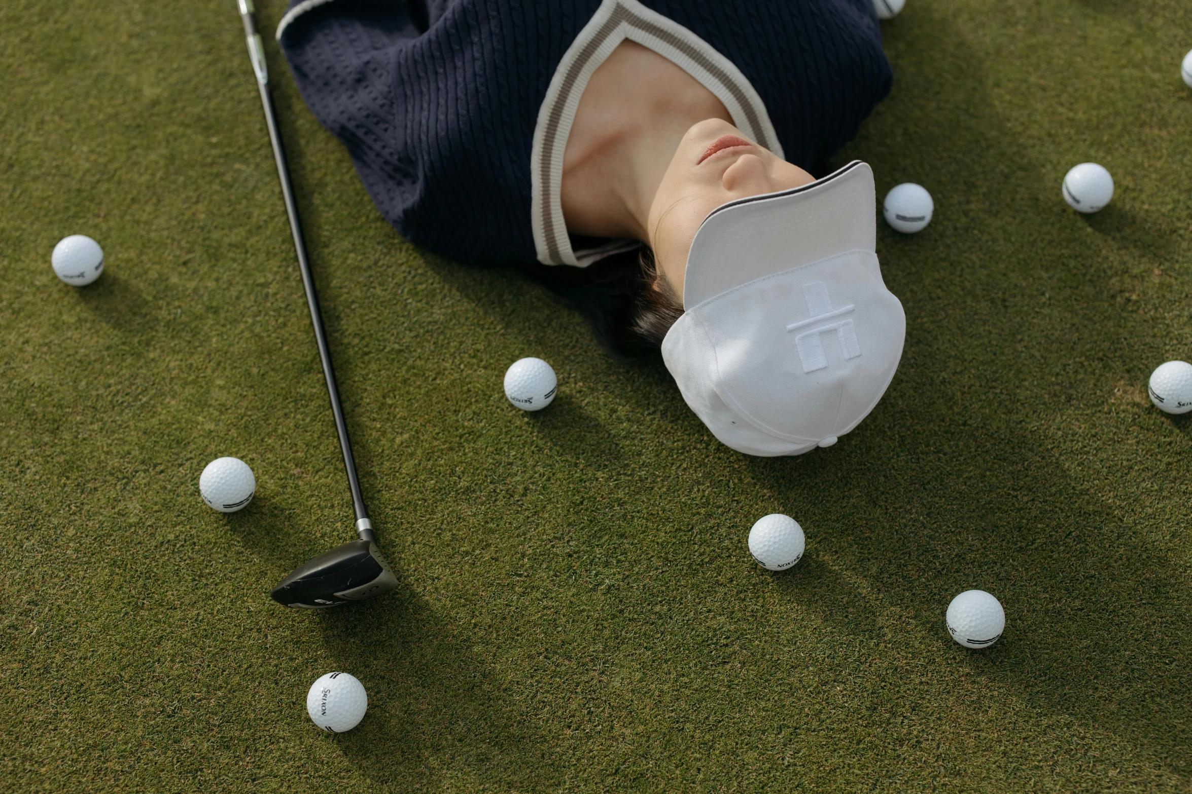 a man laying on the ground next to a bunch of golf balls, by Julia Pishtar, pexels contest winner, visor covering eyes, avatar image, kim hyun joo, offputting