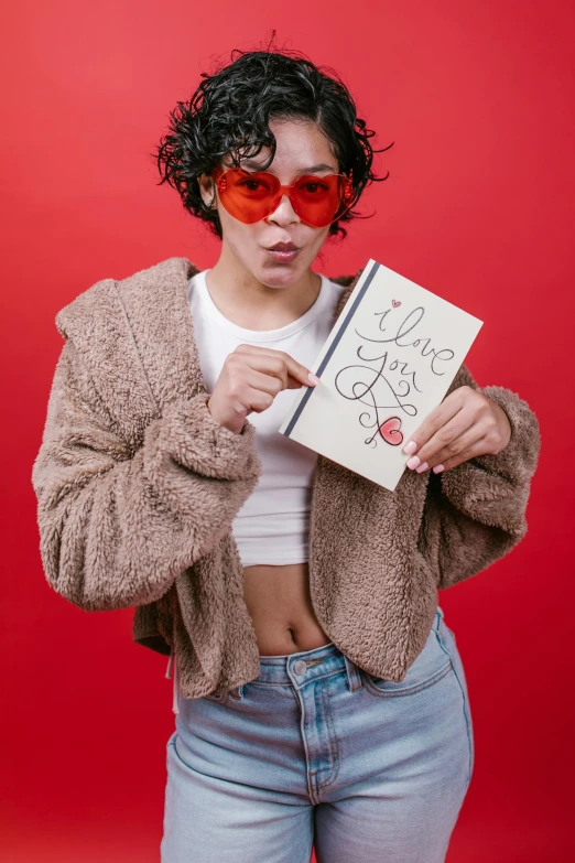 a woman holding a book in front of her face, an album cover, inspired by Ion Andreescu, trending on pexels, red sunglasses, jacket over bare torso, portrait androgynous girl, coloring book style