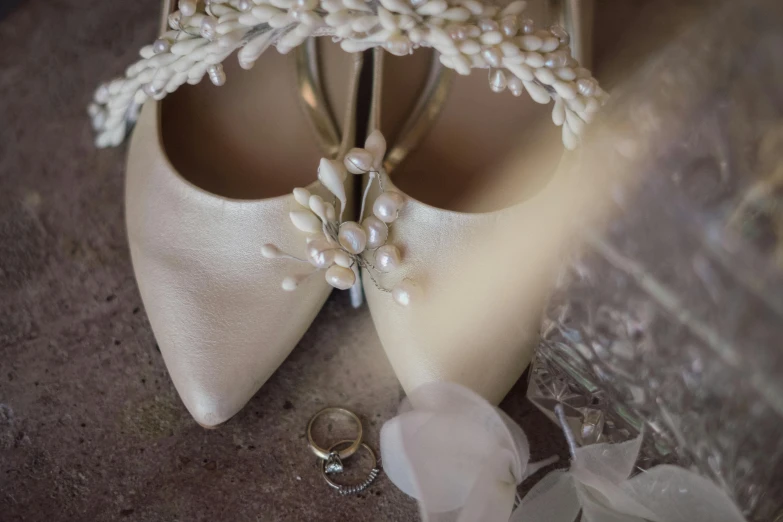 a close up of a pair of wedding shoes, by Gwen Barnard, pexels contest winner, renaissance, birdseye view, pearls and shells, rings, silver，ivory