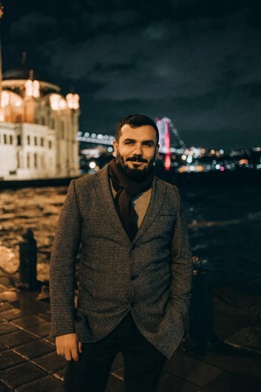 a man standing next to a body of water at night, an album cover, inspired by Nadim Karam, pexels contest winner, hurufiyya, wear an elegant mustach, istanbul, portrait of a handsome, artem