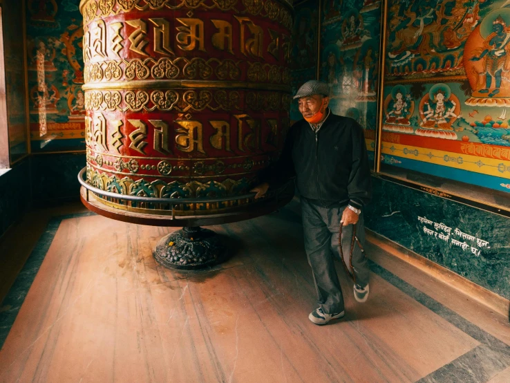 a man standing in front of a large bell, unsplash contest winner, cloisonnism, thangka, marble room, 🦩🪐🐞👩🏻🦳, an oldman