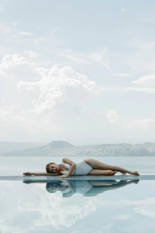 a woman laying on the edge of a swimming pool, by Julian Allen, santorini, floating in the sky, slate, grey