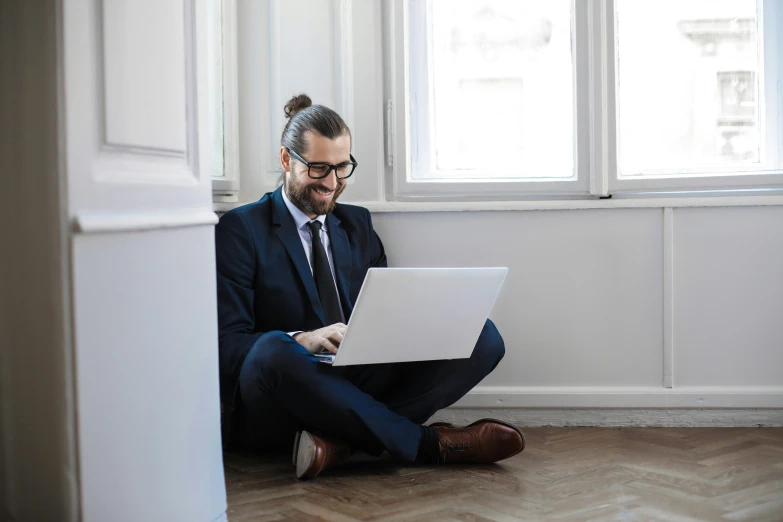 a man sitting on the floor using a laptop, by Alice Mason, pexels contest winner, in suit with black glasses, aboriginal australian hipster, slight overcast, casey cooke