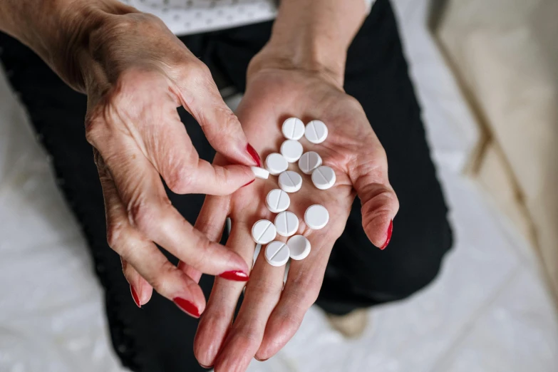 a woman holding a handful of pills in her hands, by Emma Andijewska, pexels, antipodeans, 15081959 21121991 01012000 4k, instagram post, nursing home, white stones