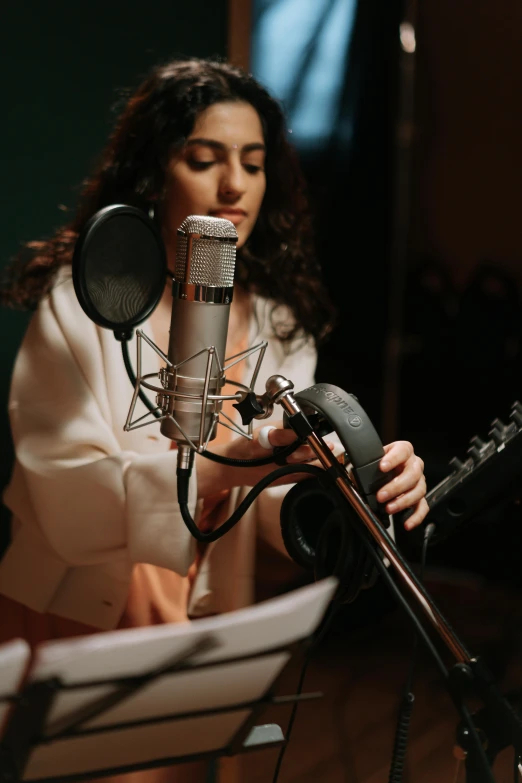 a woman that is sitting in front of a microphone, an album cover, trending on pexels, behind the scenes photo, curls, cinematic medium shot, low quality photo