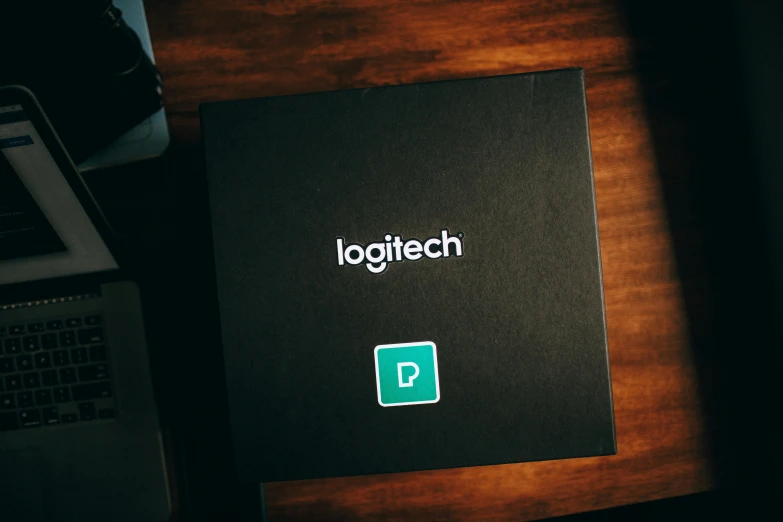 a laptop computer sitting on top of a wooden desk, patch logo, inside its box, magitech, very dark background