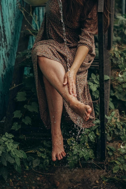 a woman sitting on a chair in the rain, inspired by Elsa Bleda, pexels contest winner, renaissance, barefoot in sandals, wearing a dress made of vines, brown skin like soil, dirty nails