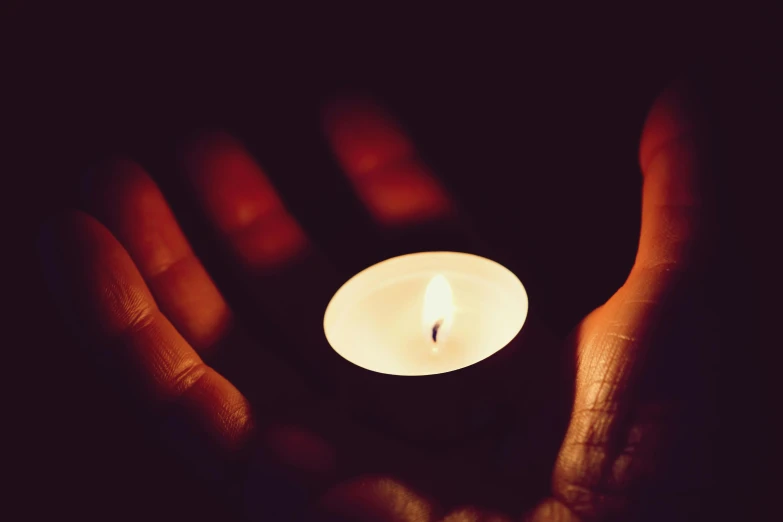 a person holding a lit candle in their hands, instagram photo, high-resolution, 5 feet away, somber lighting