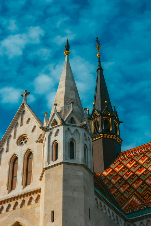 a church with two steeples and a blue sky in the background, by Bertalan Székely, trending on unsplash, budapest, intricate detailed roof, yellow and red color scheme, square