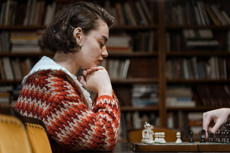 a woman sitting at a table playing a game of chess, a portrait, by Helen Stevenson, unsplash, figuration libre, maisie williams, the librarian, film still promotional image, looking from side!