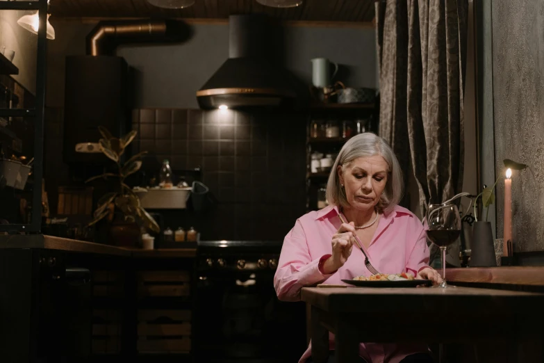 a woman sitting at a table with a plate of food, pexels contest winner, lights off, 2 0 2 1 cinematic 4 k framegrab, lachlan bailey, older woman