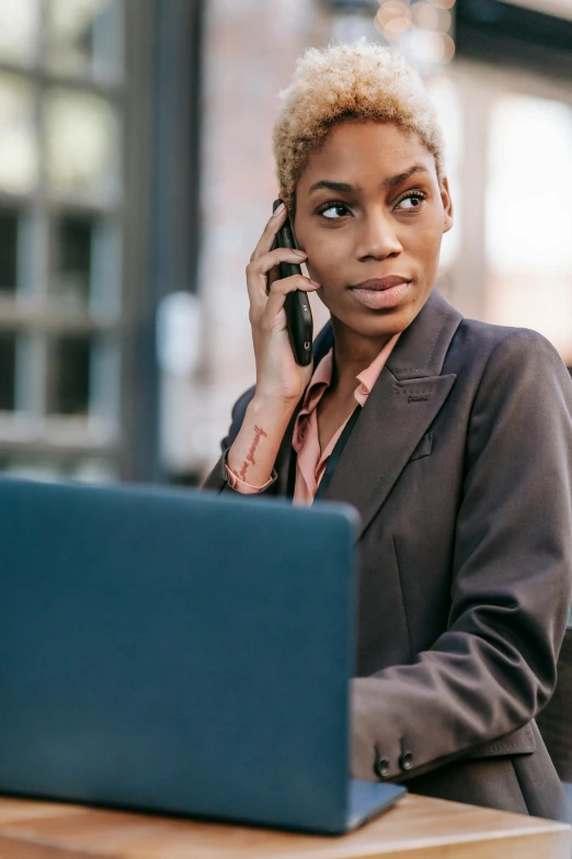 a woman sitting at a table talking on a cell phone, trending on pexels, renaissance, woman in black business suit, laptop, young black woman, a blond