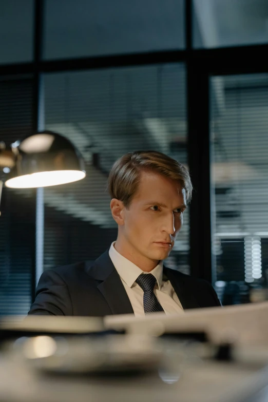 a man in a suit sitting at a desk with a laptop, trending on reddit, bauhaus, true detective, ignant, johan liebert, low light cinematic