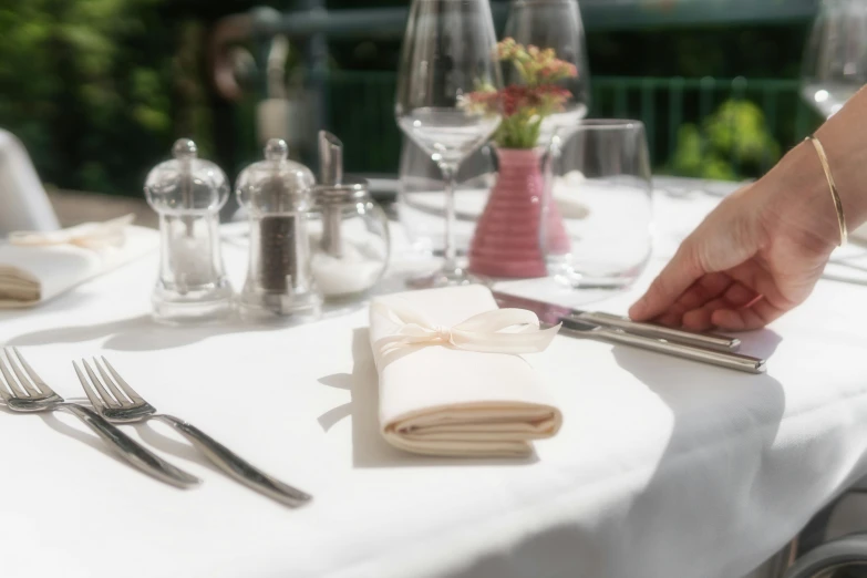 a close up of a person setting a table, at the terrace, cutlery, round about to start