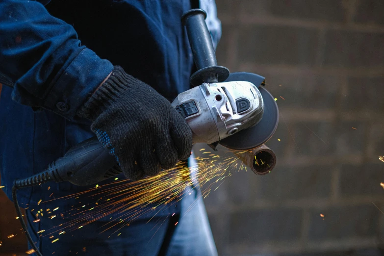 a close up of a person using a grinder, by Adam Marczyński, pexels contest winner, arbeitsrat für kunst, hyper realistic, steel, up to the elbow, background