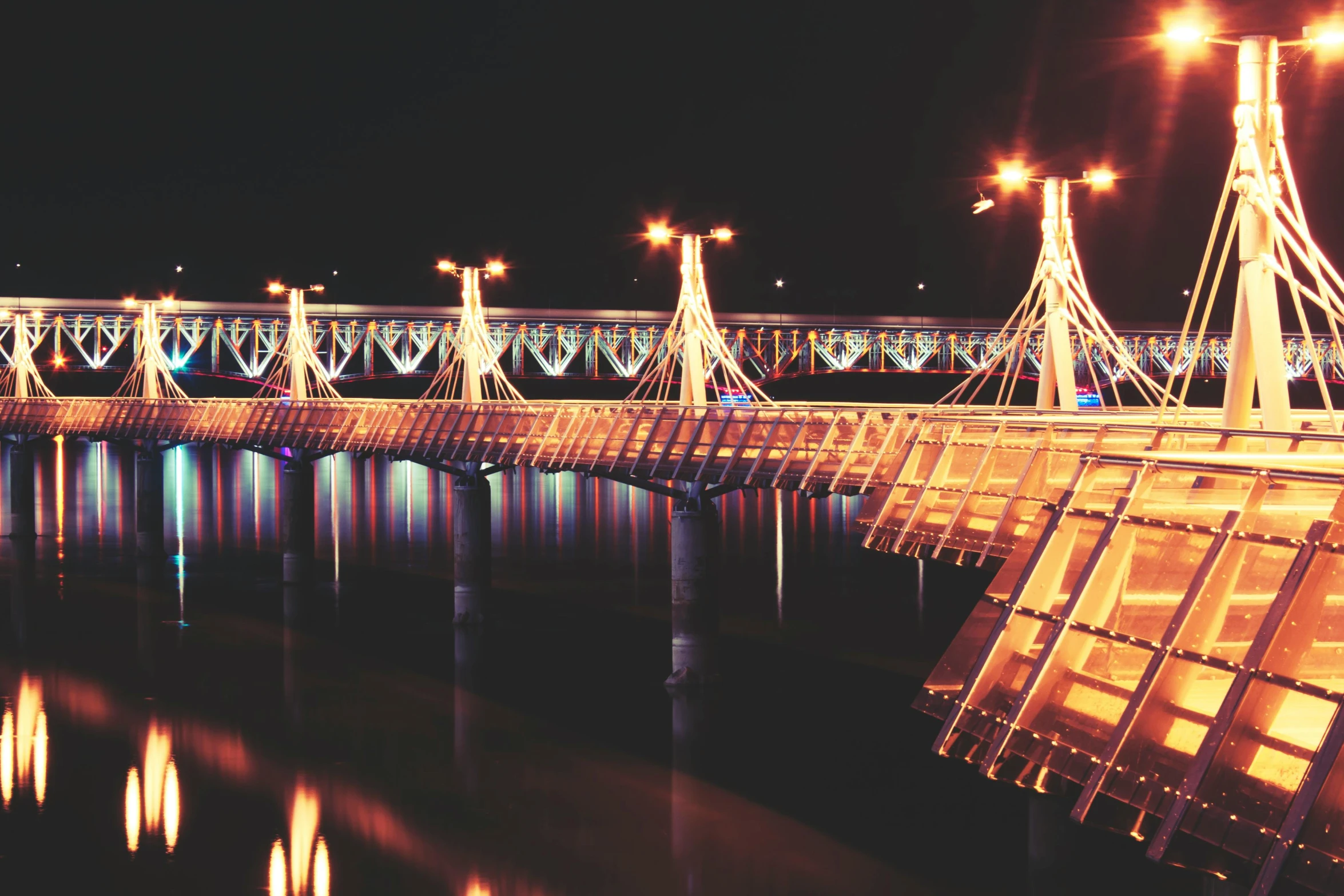 a bridge over a body of water at night, by Julia Pishtar, pexels contest winner, art nouveau, pyongyang, christmas lights, retro stylised, symetrical scene