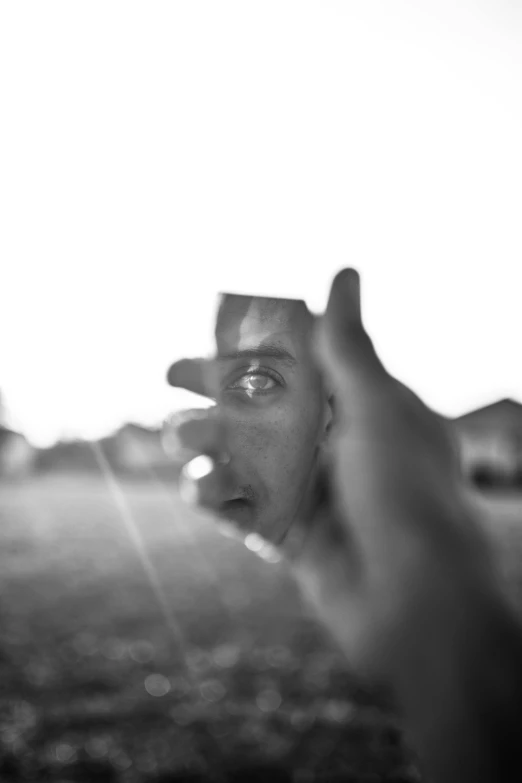 a black and white photo of a person holding a frisbee, by Thomas Fogarty, wet reflections in square eyes, pointing at the camera, looking outside, detailled face