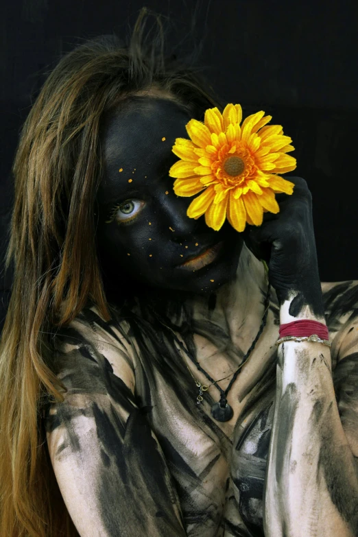 a woman holding a flower in front of her face, an album cover, inspired by Taro Yamamoto, pexels contest winner, yellow and charcoal, bodypaint, hippie girl, made of tar