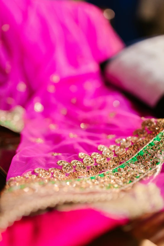 a close up of a piece of clothing on a table, flickr, dressed in a sari, pink and gold, shot with premium dslr camera, colorful picture