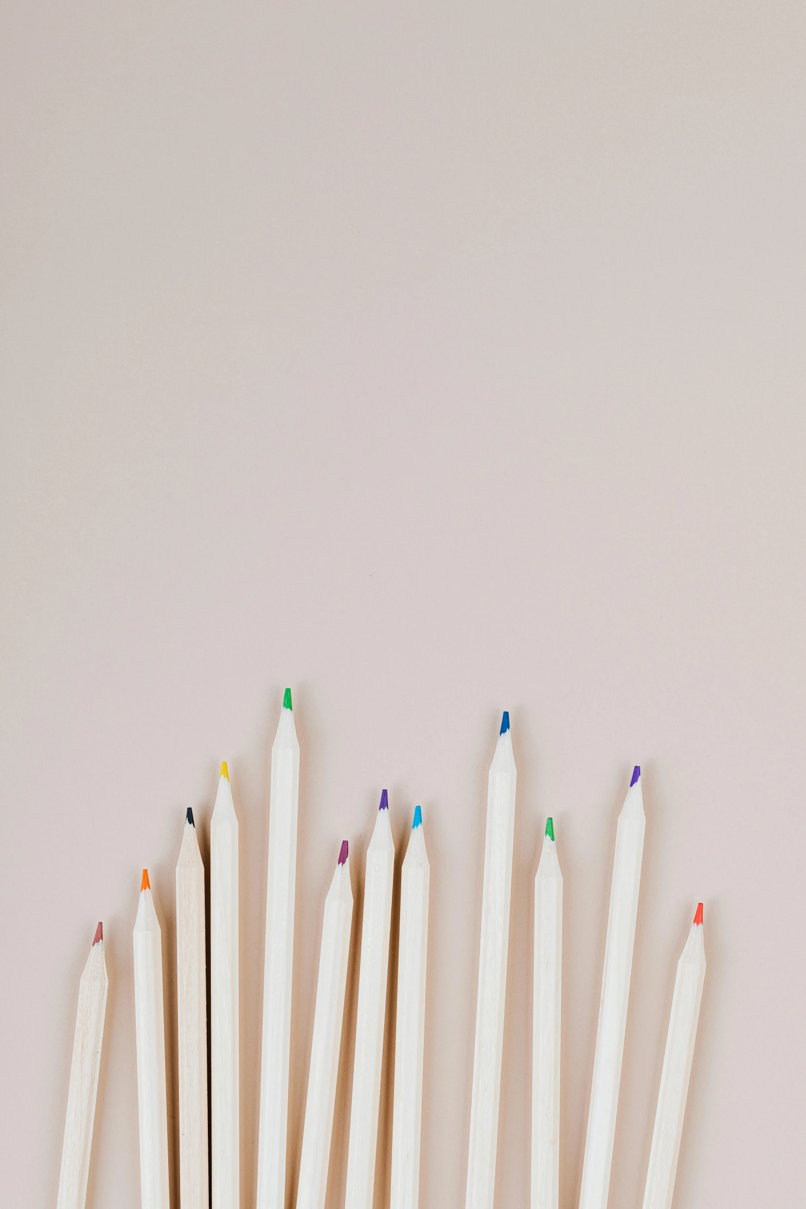 a bunch of colored pencils sitting next to each other, a minimalist painting, by Carey Morris, trending on pexels, light cream and white colors, on a pale background, top - down photograph, ilustration