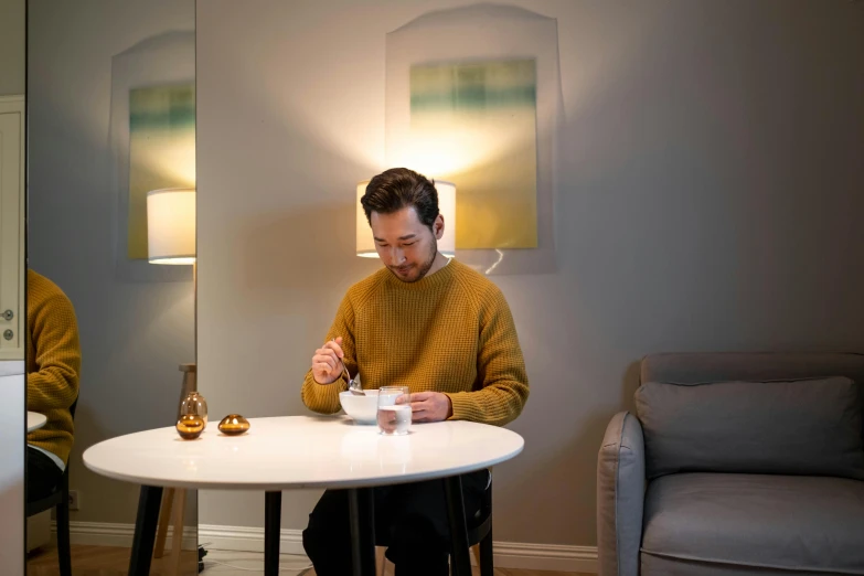 a man sitting at a table with a cup of coffee, liam brazier, cereal, illuminated, james gleeson