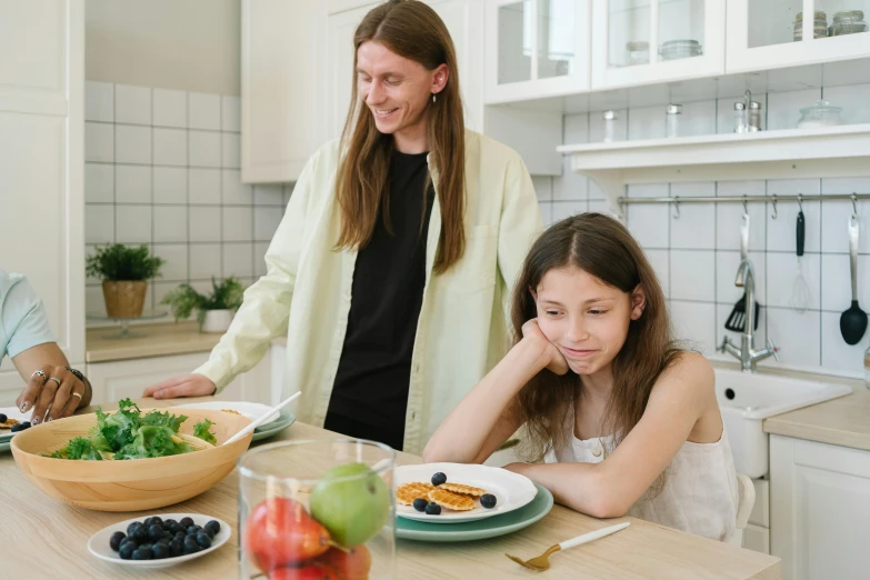 a woman and a young girl sitting at a kitchen table, pexels contest winner, anorexic figure, plates of fruit, sad man, profile image