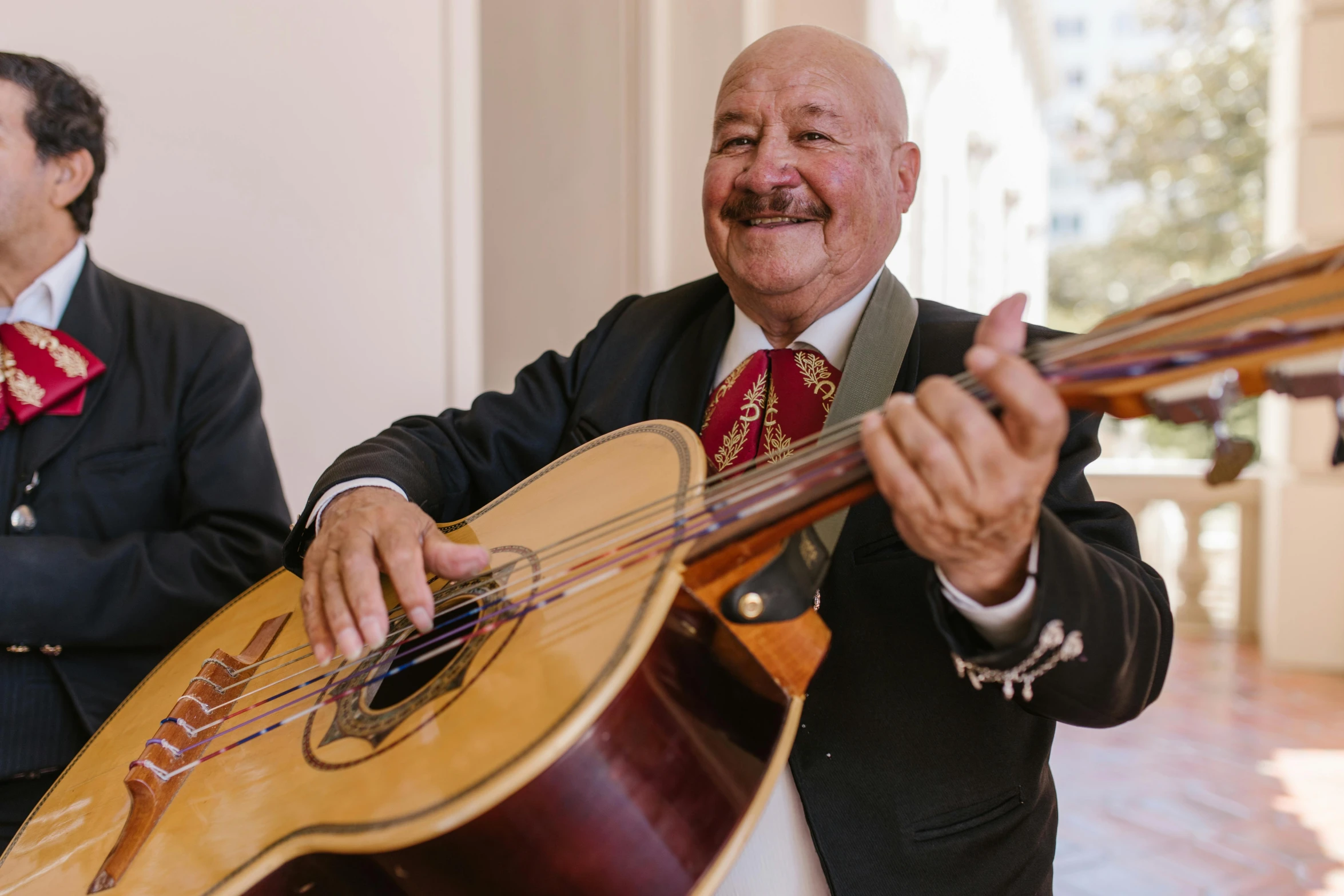 a man holding a guitar next to another man in a suit, inspired by Agustín Fernández, smiling and dancing, portrait image, thumbnail, chilean