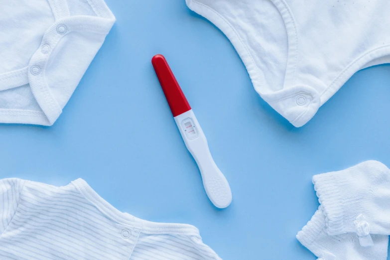 baby clothes and a thermometer on a blue background, pexels contest winner, white and red color scheme, fine point pen, pregnancy, white and blood color scheme