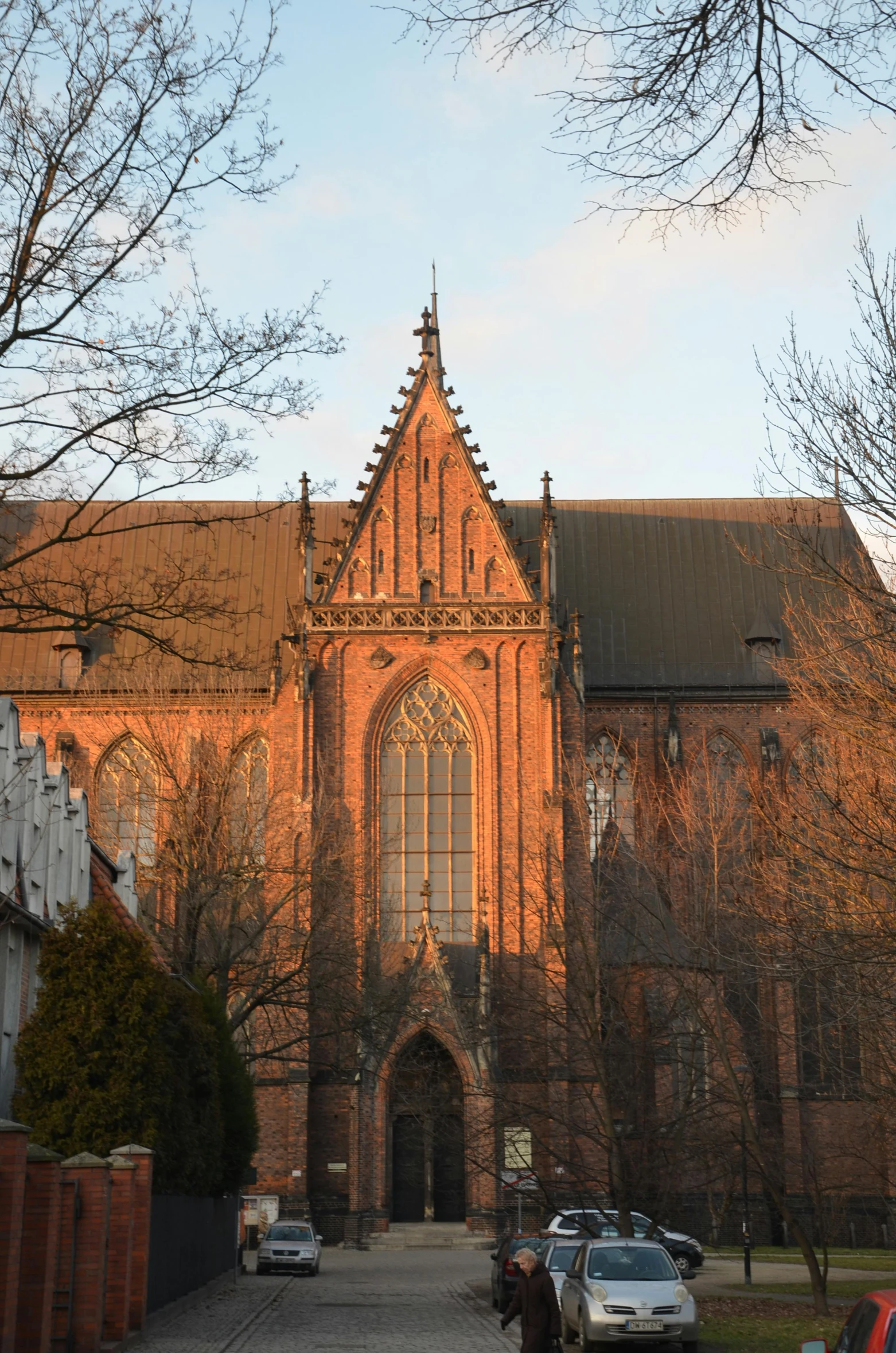 a couple of cars that are parked in front of a building, a picture, by Jan Tengnagel, pexels contest winner, romanesque, dramatic reddish light, gothic cathedral, late afternoon sun, panorama