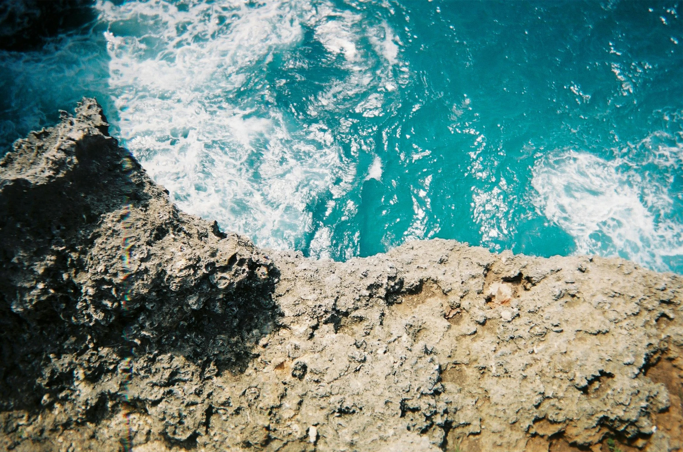 a view of the ocean from the top of a cliff, an album cover, unsplash, carribean turquoise water, highly detailded, analogue photo, geology