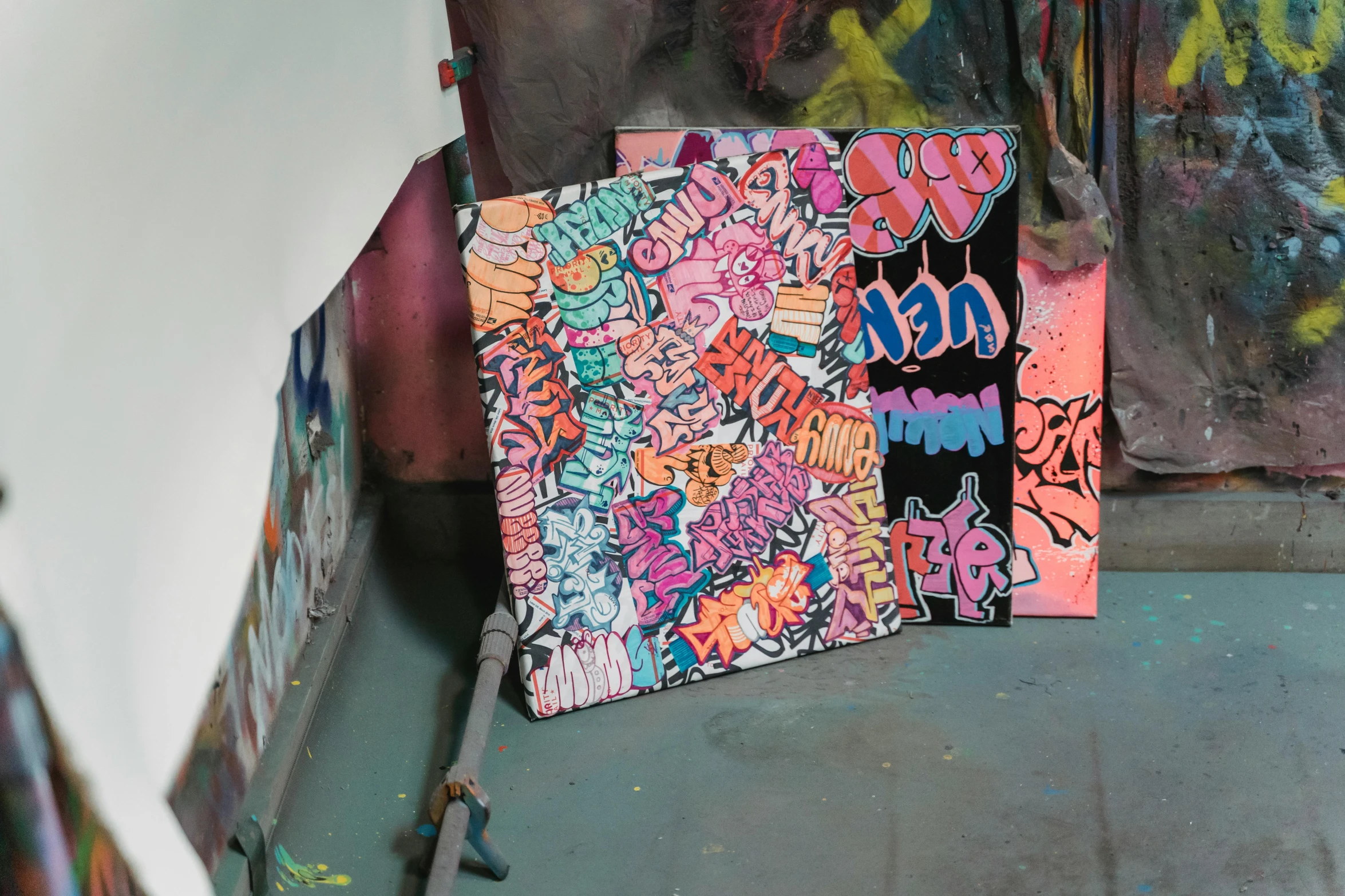 a skateboard sitting in front of a graffiti covered wall, by Tom Bonson, graffiti, stands at a his easel, studio background, multicoloured, james jean color palette