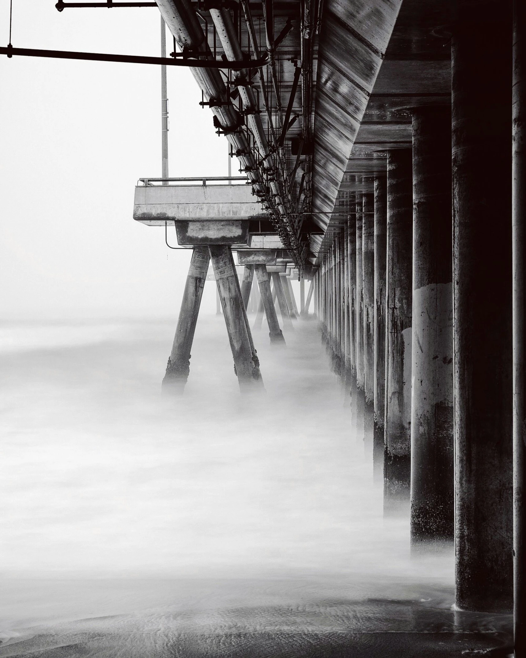 a black and white photo of a pier, unsplash contest winner, art photography, water mists, concrete pillars, medium format. soft light, southern california