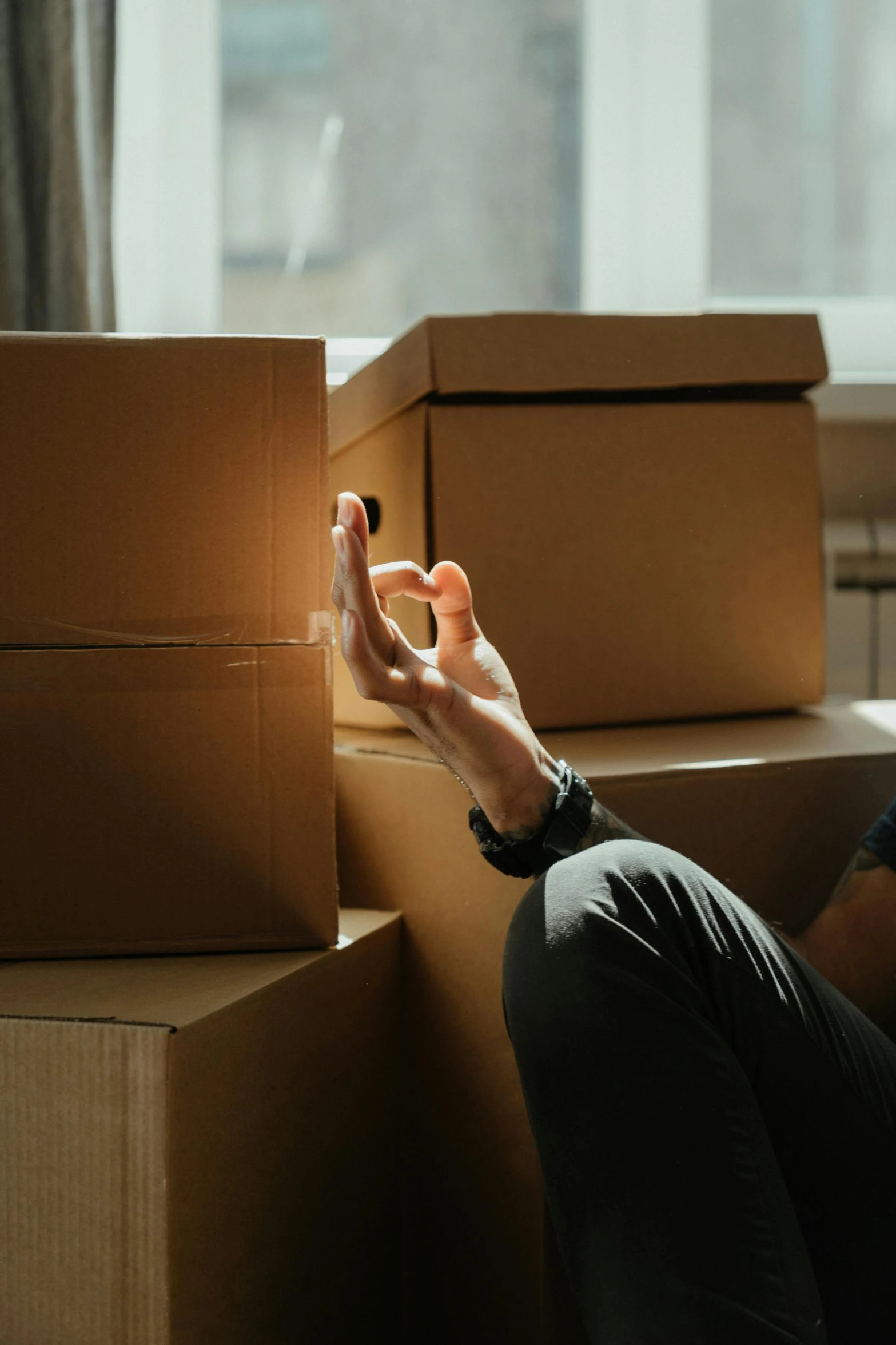 a man sitting on the floor next to a pile of boxes, pexels contest winner, sitting on man's fingertip, melbourne, long distance, light emitting from fingertips