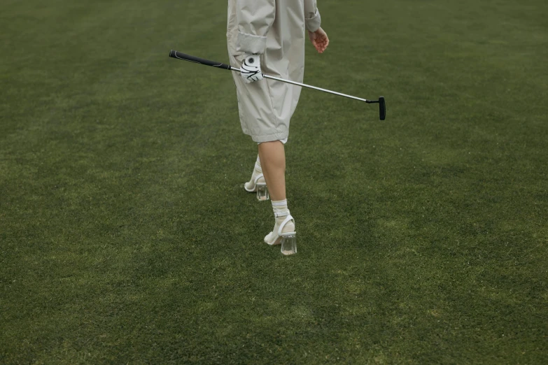 a man walking across a field holding a golf club, unsplash, photorealism, rinko kawauchi, off-white plated armor, high quality photo, lawn