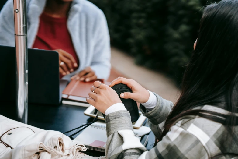 two people sitting at a table with laptops, by Emma Andijewska, trending on pexels, happening, college girls, background image, dynamic closeup, al fresco