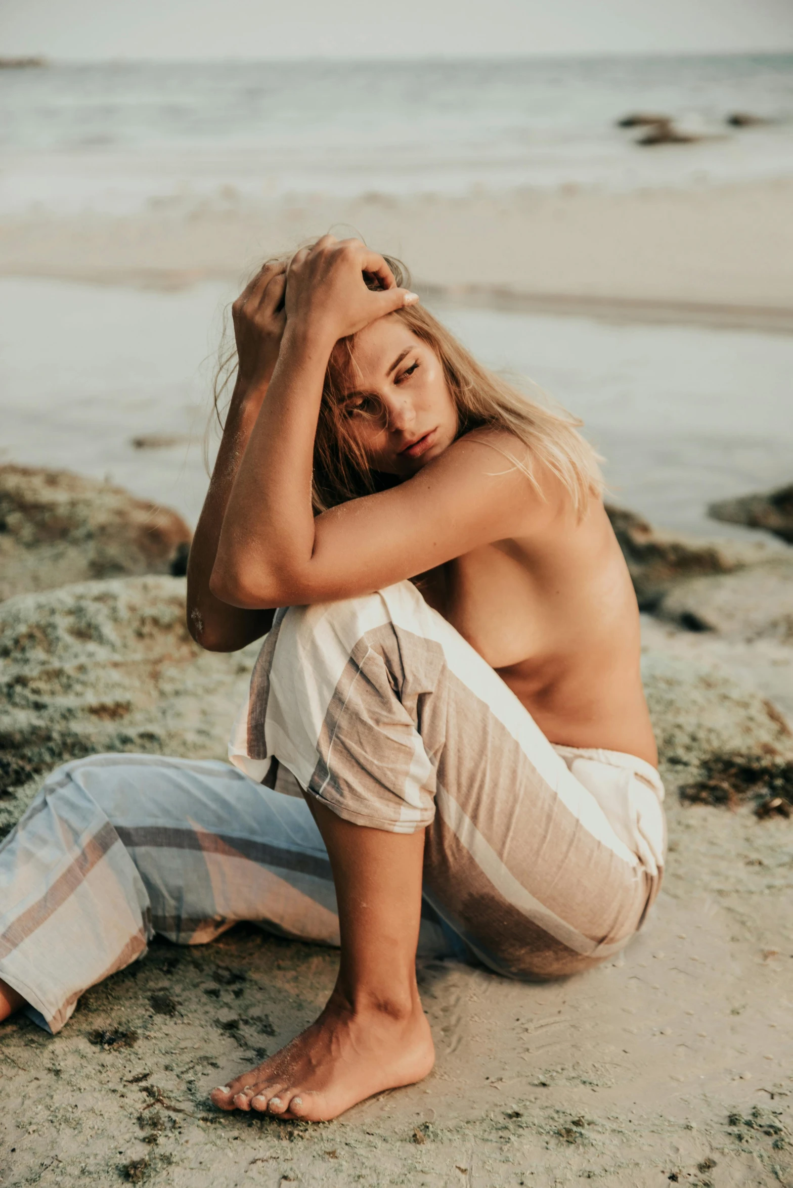 a woman sitting on top of a sandy beach, trending on pexels, renaissance, beautiful androgynous girl, worn out, blonde, toned body