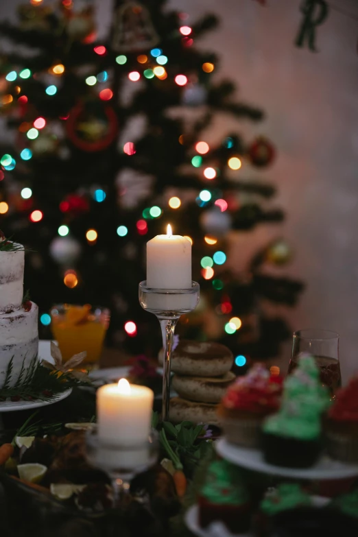 a table topped with cakes and candles next to a christmas tree, a portrait, pexels, closeup at the food, side lights, long, salt