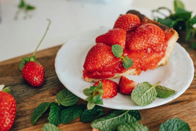 a piece of pie sitting on top of a white plate, by Emma Andijewska, pexels contest winner, hurufiyya, strawberries, mint, on a wooden plate, 🚿🗝📝