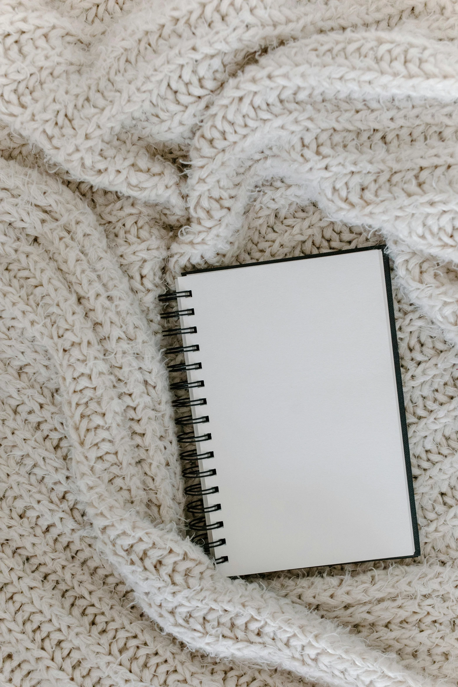 a white notebook sitting on top of a white blanket, trending on pexels, wearing an oversized sweater, thumbnail, uncropped, 1 2 9 7