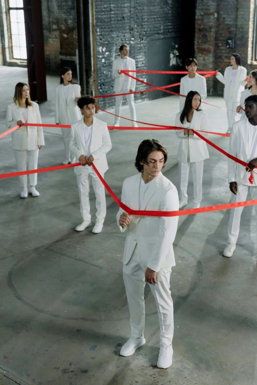 a group of people standing around a red ribbon, inspired by Vanessa Beecroft, pexels contest winner, gutai group, wearing futuristic white suit, avan jogia angel, [ theatrical ], serpentine maze