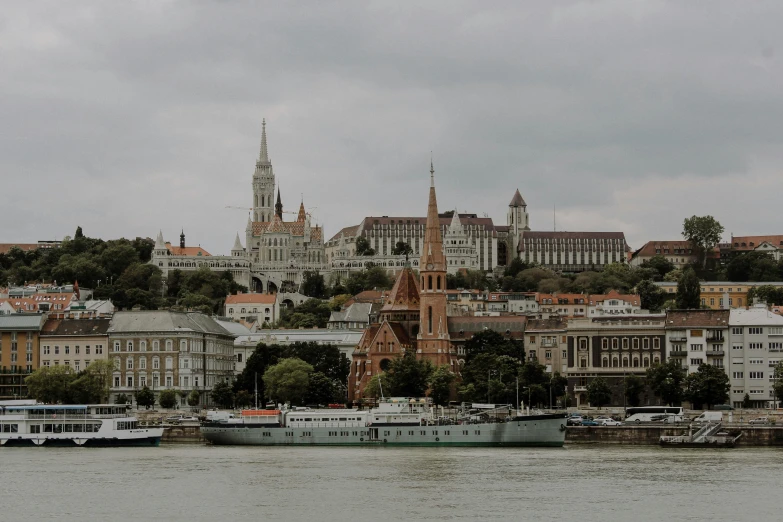 a large body of water with a city in the background, pexels contest winner, danube school, background image, moody : : wes anderson, asymmetrical spires, hills in the background