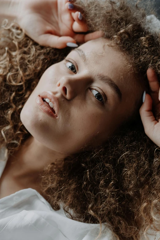 a woman with curly hair laying on a bed, trending on pexels, renaissance, exhausted face close up, portrait of teenage girl, large forehead, heavy gesture style closeup