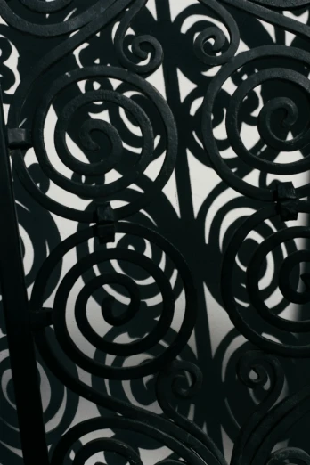 a clock that is on the side of a building, an abstract drawing, unsplash, art nouveau, iron gate door texture, black on black, spiral, photographed for reuters