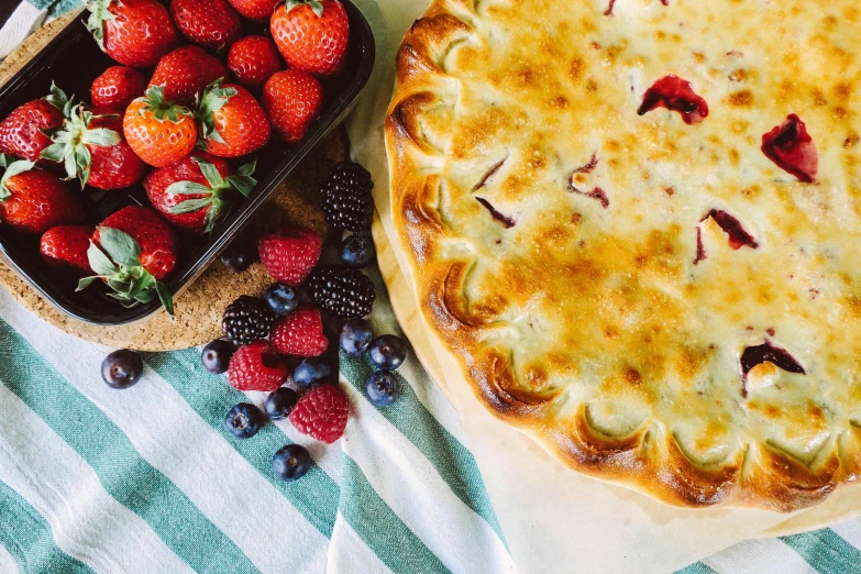 a pie sitting on top of a table next to a bowl of strawberries, 🦩🪐🐞👩🏻🦳, food photo, a brightly coloured, summer season