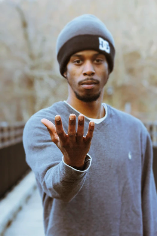 a man standing on a bridge with his hands in the air, an album cover, by Stokely Webster, unsplash, black arts movement, large friendly eyes, point finger with ring on it, headshot profile picture, thin young male