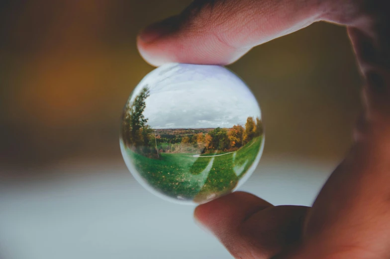 a close up of a person holding a glass ball, landscape photo, slightly realistic, distant photo