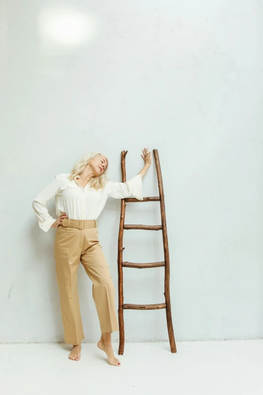 a woman leaning against a ladder leaning against a wall, trending on pexels, renaissance, brown pants, blond, white backdrop, 15081959 21121991 01012000 4k